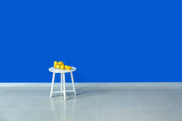 Tavolo con limoni vicino parete di colore in camera - Foto, immagini