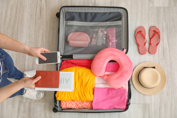 Женщина упаковывает чемодан для путешествия домой, вид сверху - Фото, изображение