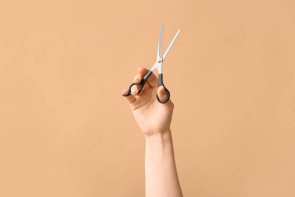 Female hand hairdresser's scissors on color background - Foto, afbeelding