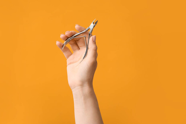 Female hand with manicure cutter on color background - Fotografie, Obrázek