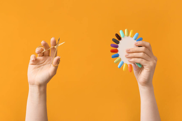 Mani femminili con forbici manicure e punte smalto su sfondo colore - Foto, immagini