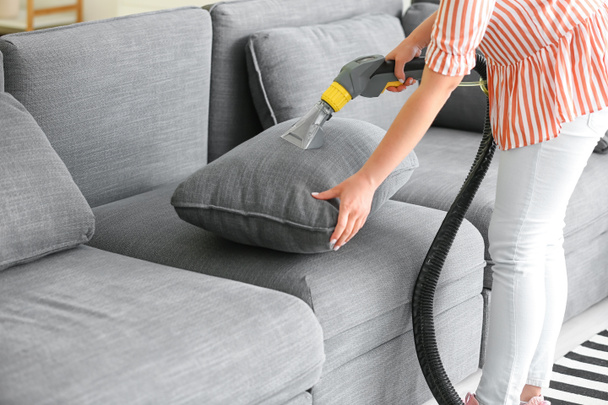 Woman removing dirt from sofa at home - Фото, изображение