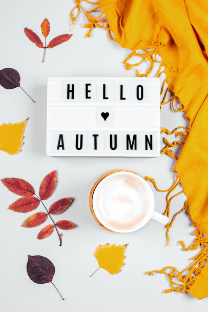 Cup of coffee, orange scafr and light box with words Hello Autumn and Colorful autumn fall leaves on grey background. Flat lay - Φωτογραφία, εικόνα