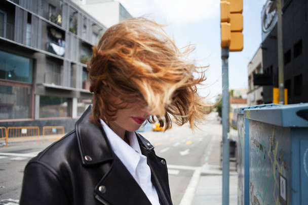 Portrait de style de vie venteux de mignonne jeune fille gaie aux cheveux roux étonnants posant dans la rue. - Photo, image