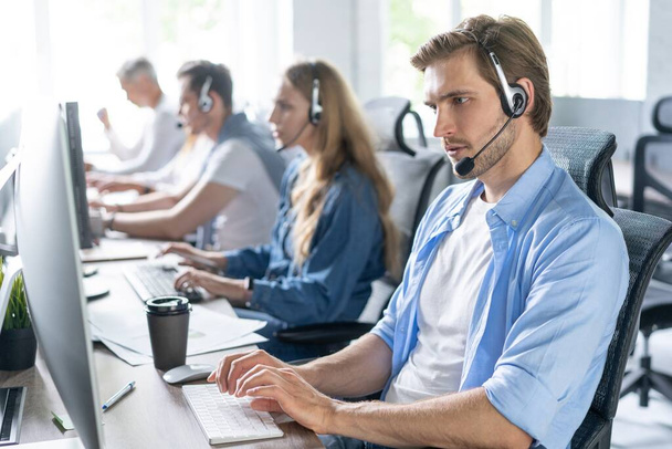 Young handsome male customer support phone operator with headset working in call center - Foto, imagen