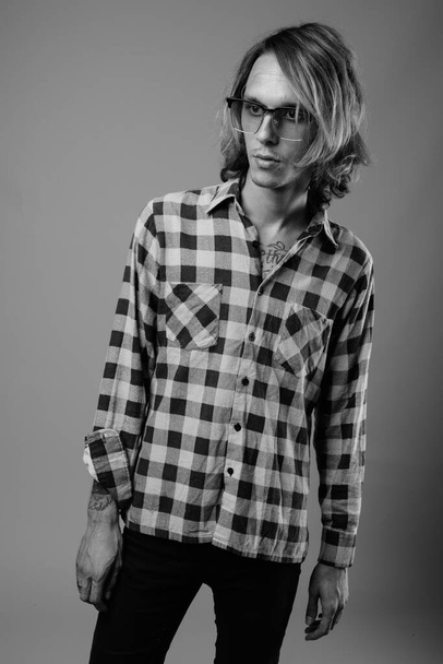 Plan studio d'un jeune homme rebelle portant une chemise à carreaux sur fond gris en noir et blanc - Photo, image