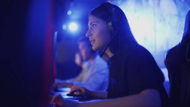 Skoncentrowany młoda kobieta grać w klubie komputerowym, gra online przez zespół. - Zdjęcie, obraz