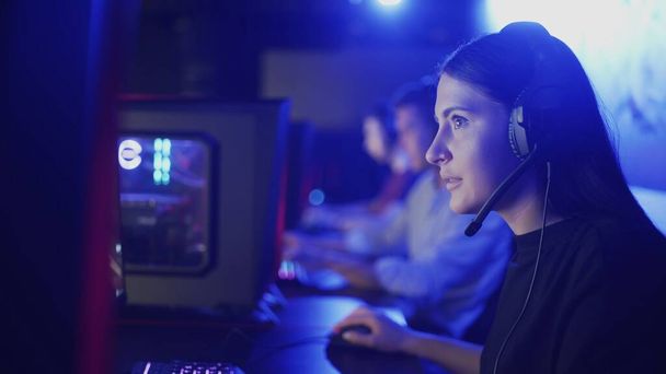 Moderní kybernetický tým účastnící se soutěže vítězí v prvním kole počítačové hry, mladá žena soustředěný výstřel - Fotografie, Obrázek