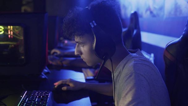Geconcentreerde jongeman zit voor de monitor en verliest hard niveau in video game in computer club - Foto, afbeelding