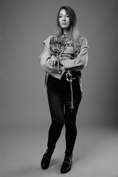 Στούντιο πλάνο των νέων όμορφη επαναστατική γυναίκα κατά γκρι φόντο σε μαύρο και άσπρο - Φωτογραφία, εικόνα