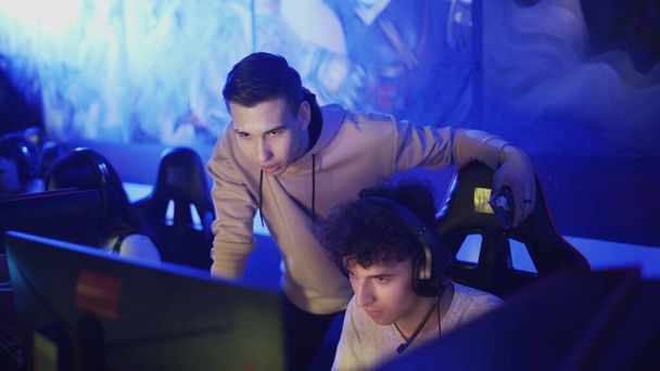 Pro Gamers allenatore dando consigli al suo amico mentre sta giocando round di videogiochi nel moderno club cybersport - Foto, immagini