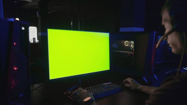 Zpět pohled na e kyber sport hráč hrát hru s monitorem zelené obrazovky a výkonný osobní počítač na stole doma - Fotografie, Obrázek