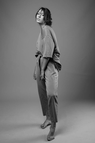 Plan studio de jeune belle femme portant des vêtements assortis sur fond gris en noir et blanc - Photo, image