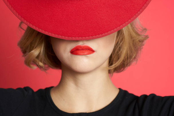 Woman covers with hat her eyes red lips close-up isolated background - Photo, Image