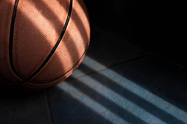 Ein orangefarbener Basketballball auf dunkelblauem Boden. Schattenzeichnung. - Foto, Bild