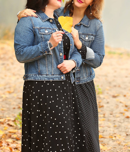 Familie look. Moeder en dochter zijn stijlvol gekleed: blauwe denim jassen en zwarte polka dot jurken buiten in de herfst. Mode en schoonheid voor vrouwen. - Foto, afbeelding