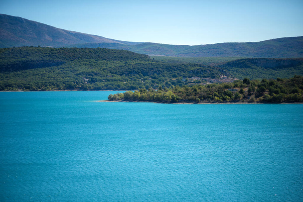 Панорамный вид на озеро Сент-Круа на юге Франции. Искусственное озеро 1973 года. Мбаппе на озере с видом на маленький город Прованс. Почувствуйте тихую воду и голубое небо. Мутаны из Альп. - Фото, изображение