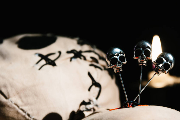 Закройте магическую куклу Вуду, лежащую на деревянном столе на черном фоне со свечами - Фото, изображение