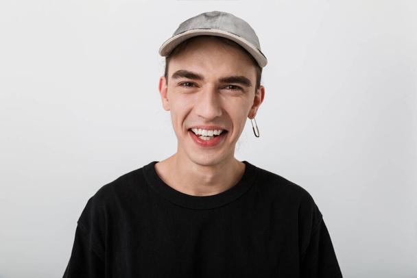 Portrait closeup of pleased young man wearing black clothes looking at camera and laughing over white background - Foto, imagen