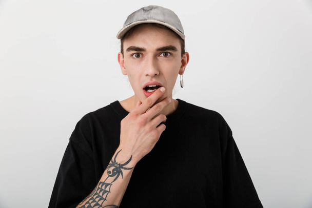 Portrait closeup of shocked young man wearing black clothes looking at camera with open mouth over white background - Fotografie, Obrázek