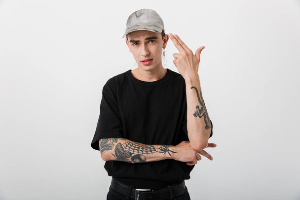 Portrait of sassy young man wearing black clothes looking at camera and pointing fingers himself over white background - Fotografie, Obrázek
