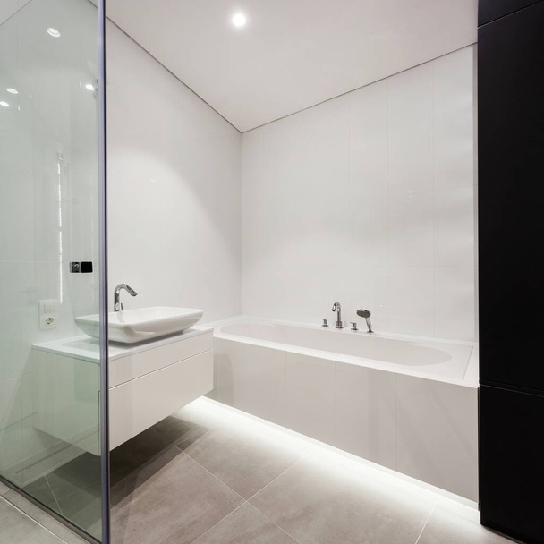Side view eleme a modern ház üveg ajtó kortárs belsőépítészeti fürdőszoba, fehér fürdő, mosogató a pulton ellen üres másolás tér fal - Fotó, kép