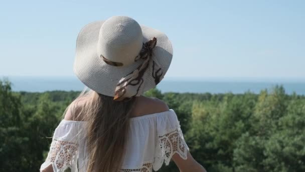 Nainen hatussa nauttimassa kesäpäivästä merenrannalla - Materiaali, video