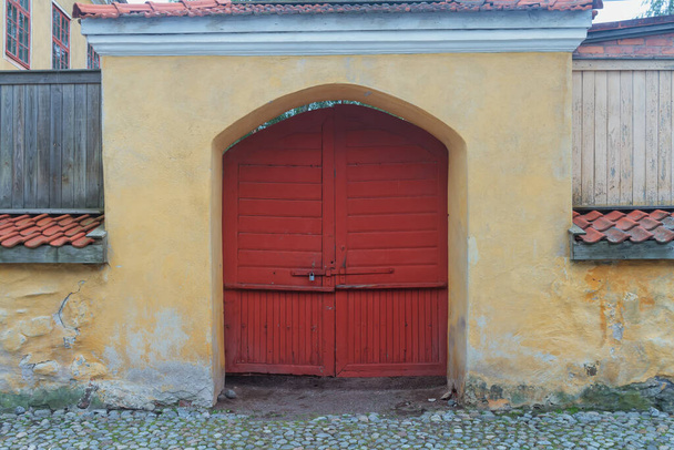 Egy régi kapu és bezárt fa piros ajtók a régi város Rauma, Finnország. A történelmi óváros tele van ilyen részletekkel.. - Fotó, kép
