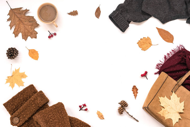秋の組成-スエードバッグ、居心地の良い服、秋の葉やコーヒー白の背景に隔離され、フラットレイアウト、トップビュー、コピースペース。季節の秋のコンセプト. - 写真・画像