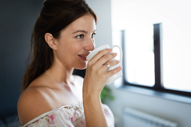 Beautiful young woman enjoys her cup of tea or coffee - Фото, зображення