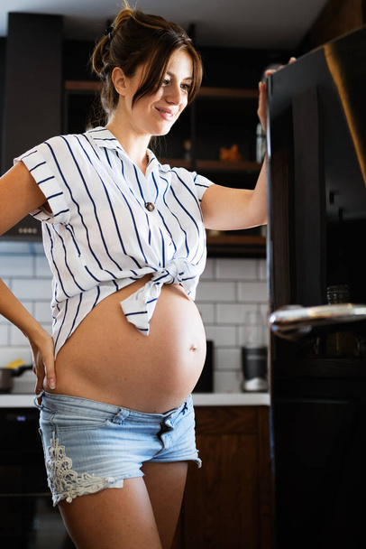 Young beautiful hungry pregnant woman looking for food in refrigerator - Foto, immagini