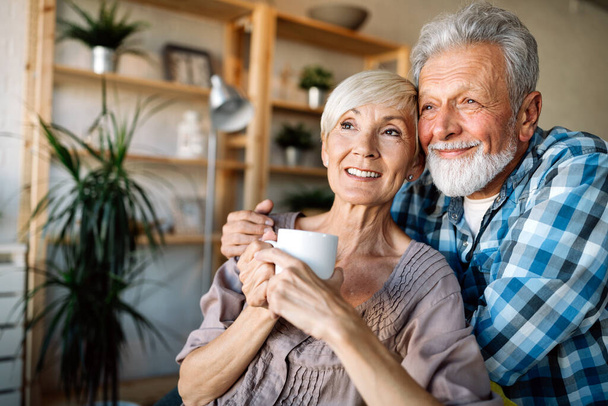 Happy smiling senior couple embracing together and enjoying retirement at home - Foto, Imagem