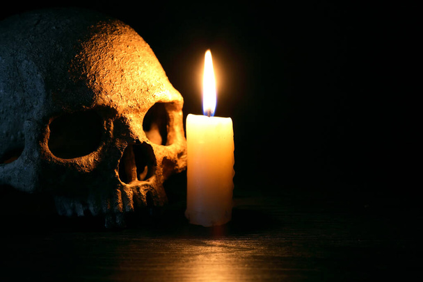 Vintage still life with lighting candle near human skull - Foto, immagini