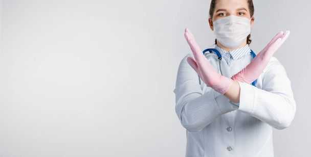 Młoda piękna lekarka w białym płaszczu i różowych jałowych rękawiczkach pokazuje gest zatrzymania na białym tle. Powiedz, żadnych chorób wirusowych. Skopiuj miejsce na tekst - Zdjęcie, obraz