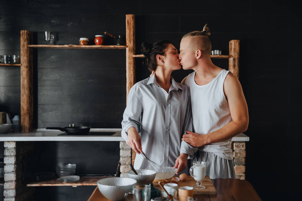 若いカップルはキッチンで一緒に健康的な食べ物を調理するのが大好きです。キスをしながら - 写真・画像