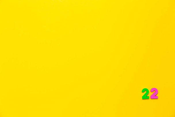 Zielona plastikowa zabawka numer dwadzieścia dwa znajduje się w prawym dolnym rogu na żółtym tle. - Zdjęcie, obraz