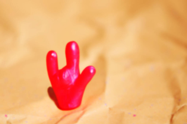 Defocused photo of a bright toy hand with "I love you" gesture.  Space for lettering and design - Foto, Bild