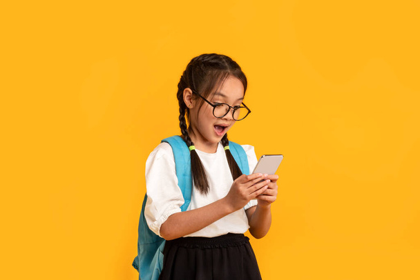 Ekscytowany azjatycki dzieciak gra w gry mobilne na smartfonie w studio - Zdjęcie, obraz