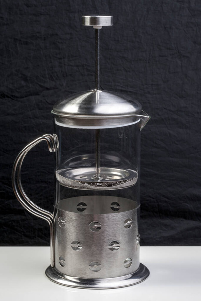 Французская пресса изолирована на черном фоне. Хромированный чайник со стеклянной фляжкой для приготовления чая и кофе - Фото, изображение