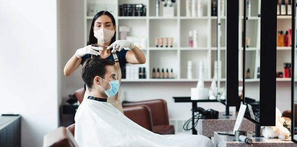 Fryzjer i klient mężczyzna w maskach ochronnych w salonie - Zdjęcie, obraz