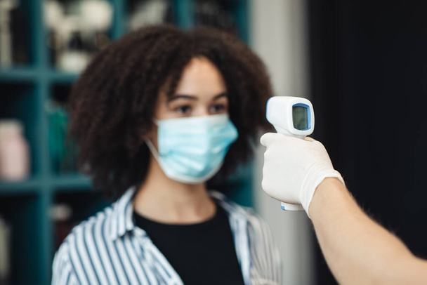 Joven mujer negra en máscara médica recibiendo detección térmica - Foto, Imagen