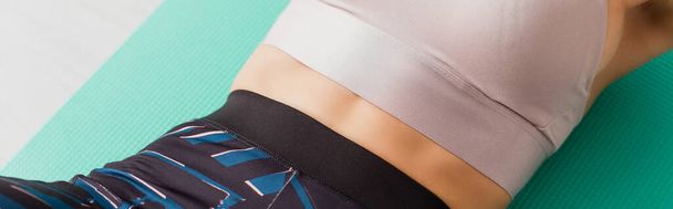 Panoramic crop of woman in sportswear lying on fitness mat  - Fotografie, Obrázek