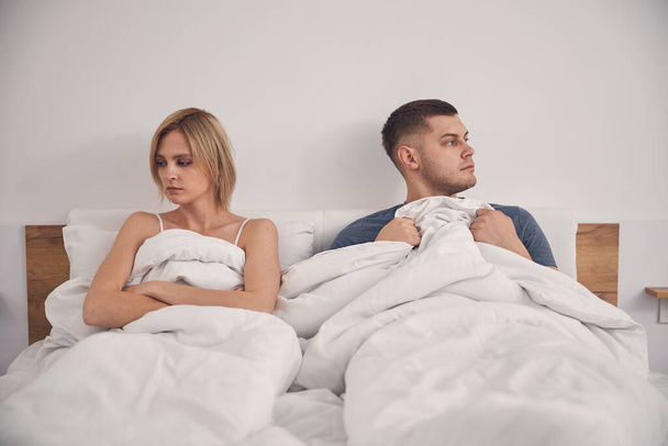 Young attractive couple staying in bed looking sad - Photo, Image