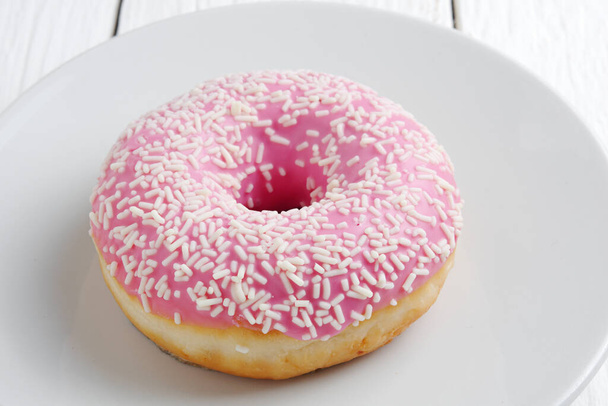 Donut rosa com polvilhas em uma placa no fundo colorido close-up - Foto, Imagem
