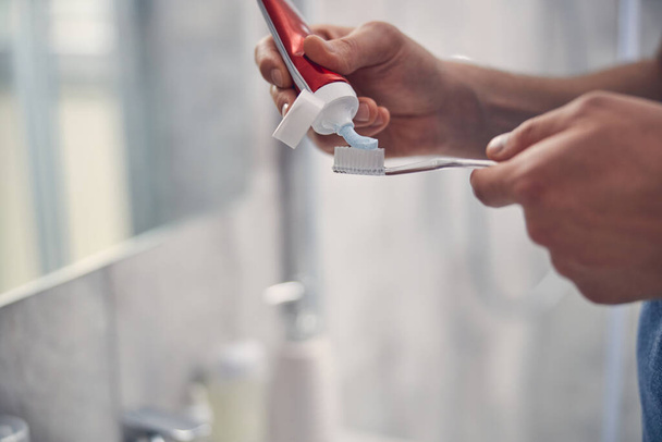 Дві руки людини, які використовують речовину для чищення зубів
 - Фото, зображення