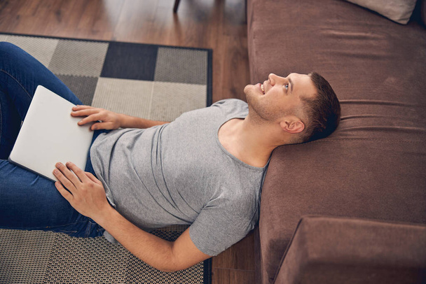 Привлекательный брюнетка мужчина расслабляется на ковре в одиночку - Фото, изображение
