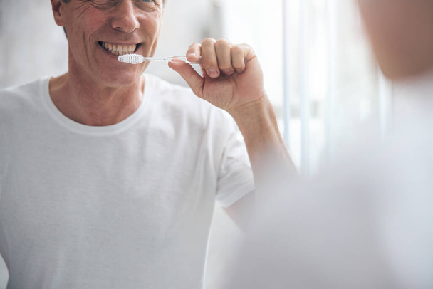 Iloinen keski-ikäinen mies säilyttää suuhygieniansa - Valokuva, kuva