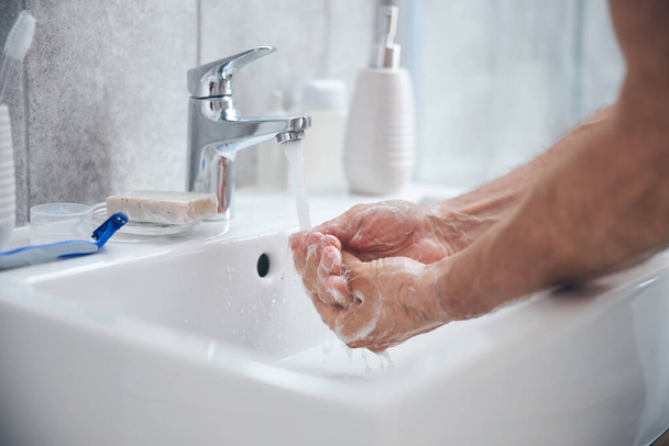Homem segurando suas palmas de xícara sob água corrente - Foto, Imagem