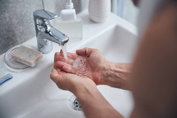 Muž si čistí ruce nad umyvadlem - Fotografie, Obrázek
