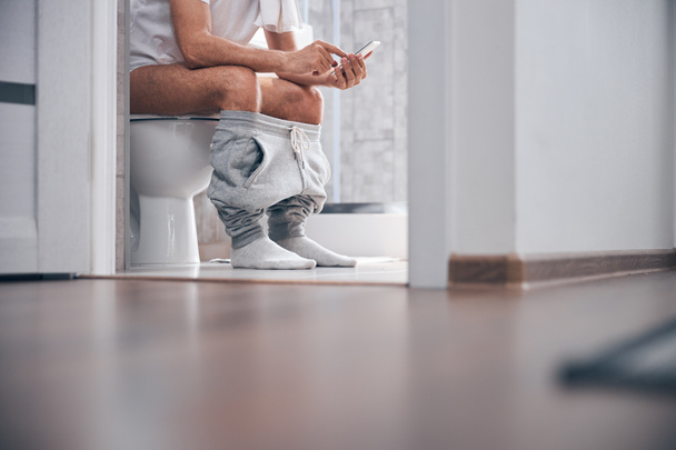 Man using his gadget in the water closet - Photo, image